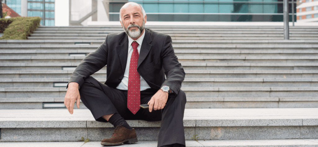 Holding Familiar A estratégia definitiva para proteção de bens e eficiência tributária na sucessão 1 Imagem de um empresário sentado na escadaria do Condomínio Empresarial